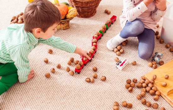 Children aggregate nuts in a toy train and learn to count sitting on the floor in kindergarten. Freight train concept